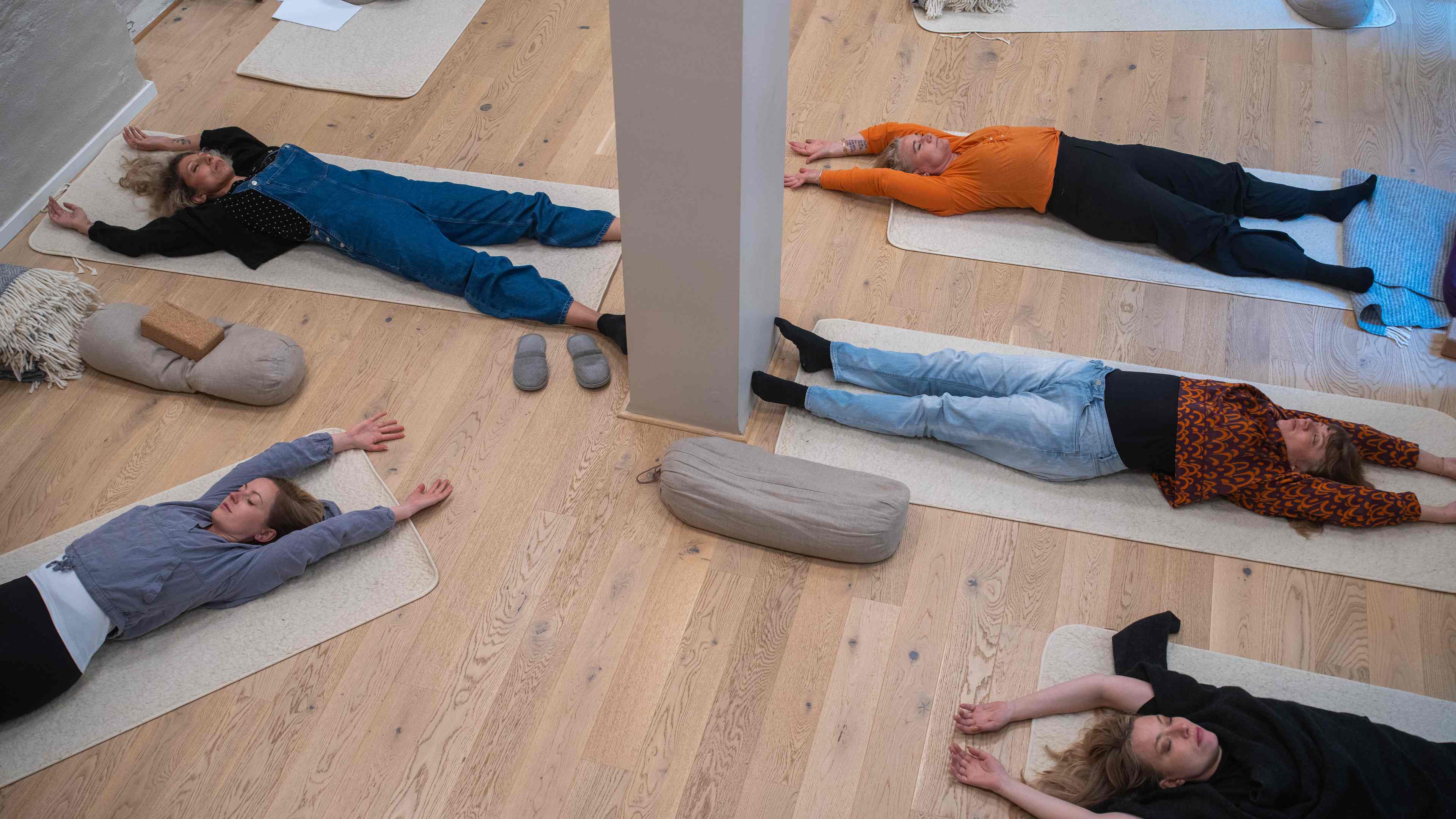 Gruppövning i kroppsnärvaro - kvinnliga deltagare ligger på yogamattor, fotade snett ovanifrån
