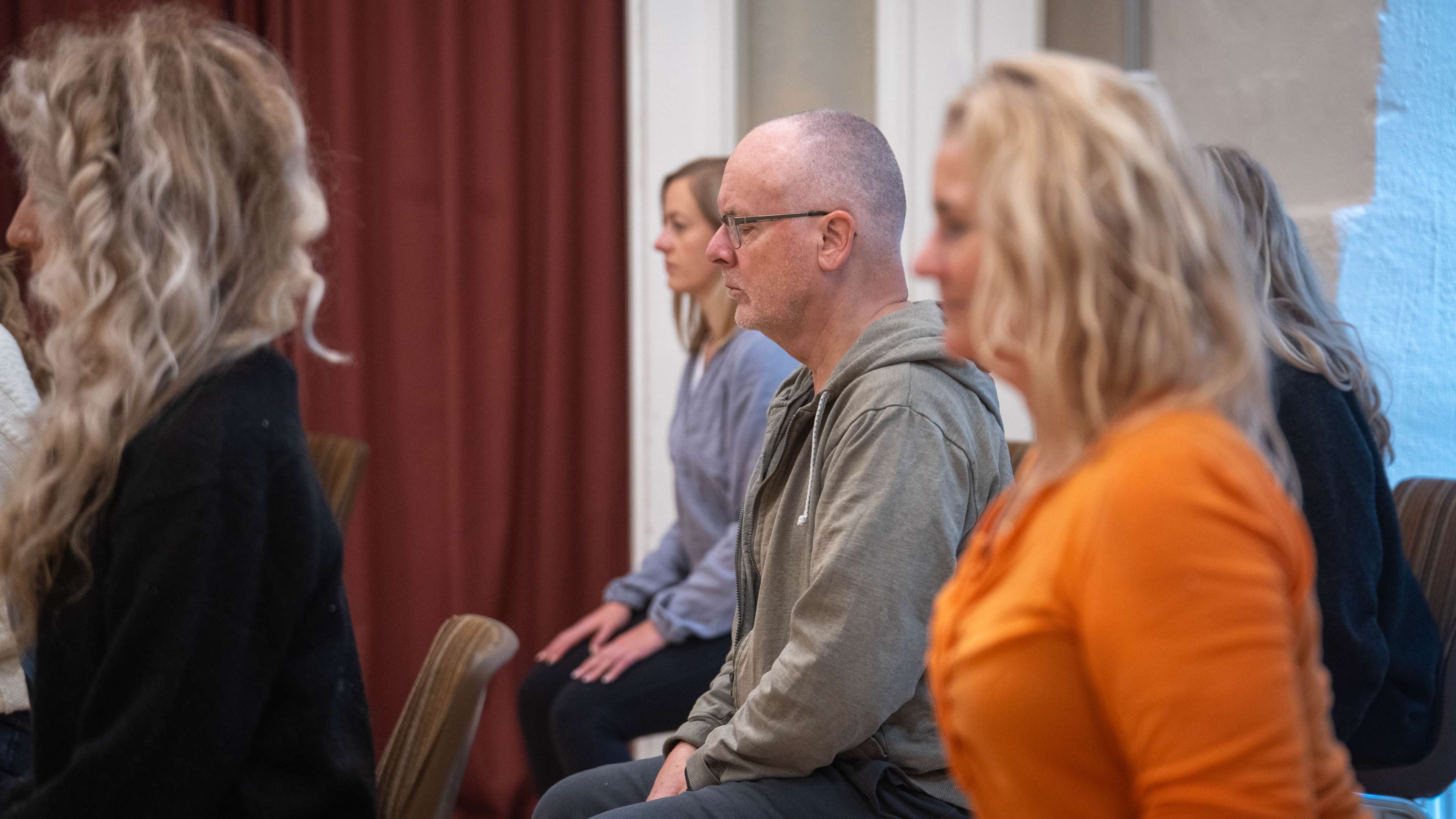Kursdeltagare i sittande kroppsnärvaroövning - man med fokuserad blick nedåt
